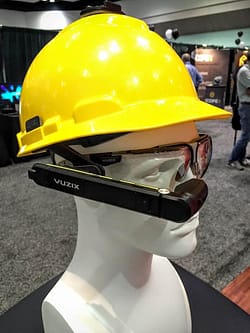 An image showing a mannequin head wearing a yellow hardhat and a pair of Vuzix augmented reality glasses.